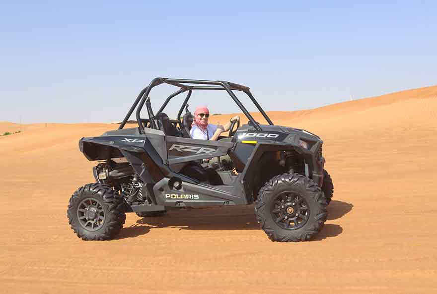 Women posing for a picture while riding a Dubai Desert Dune Buggy.