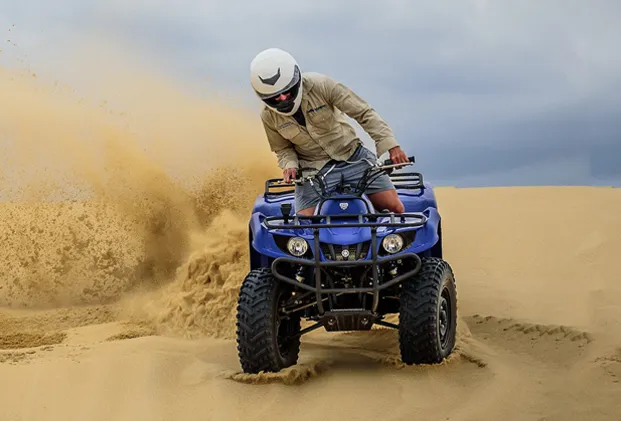 Rider parked a Quad Bike Dubai while the tinted sky complementing the scene
